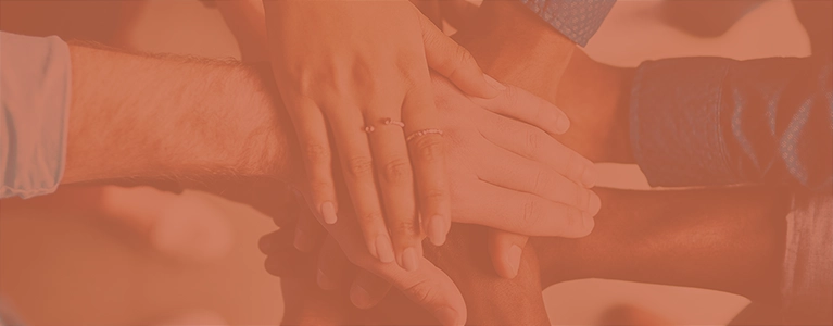 A photo of diverse hands stacked on top of each other to symbolize a team working together.