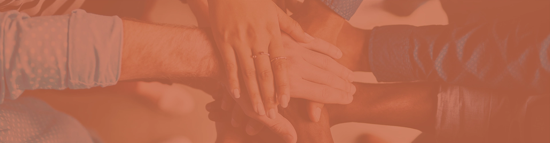 A photo of diverse hands stacked on top of each other to symbolize a team working together.